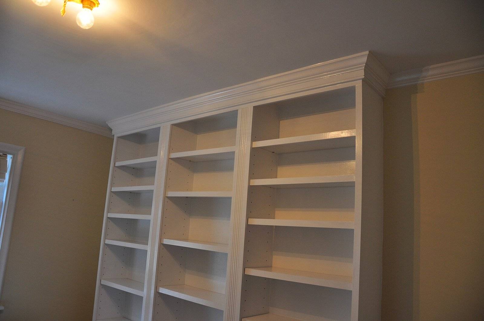 A wall of white built-in bookcases with crown molding along the top