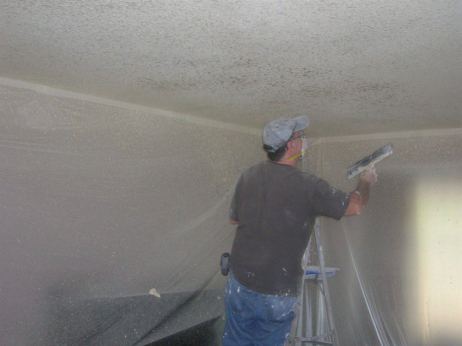 A man on a ladder skimming a ceiling