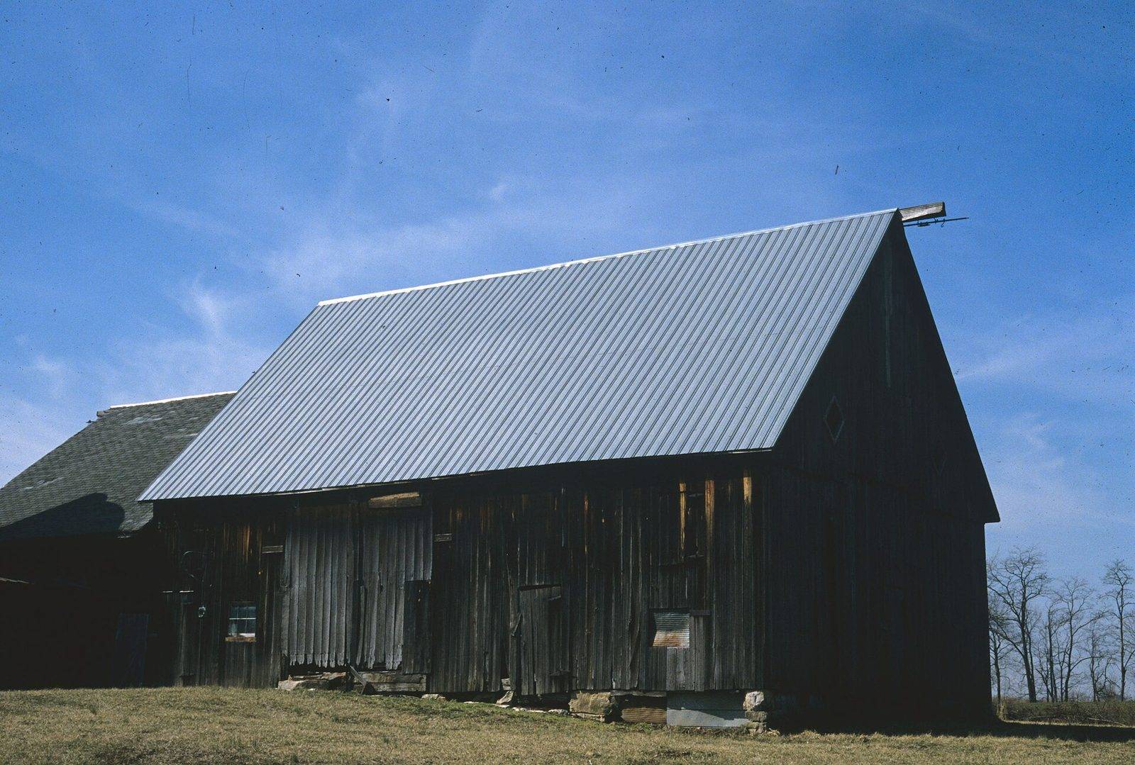 Weathered wooden barn with a ribbed metal panel roof