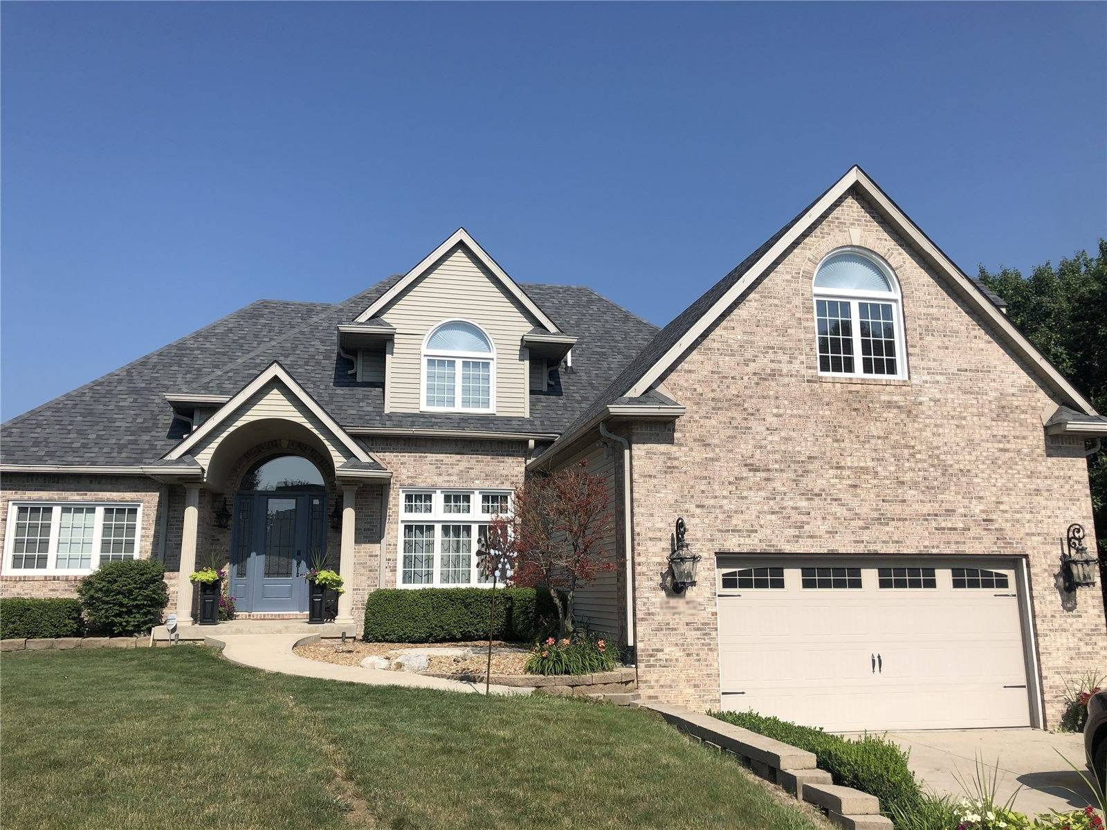 Brick and stone house with a gray shingle roof where the valley was rebuilt