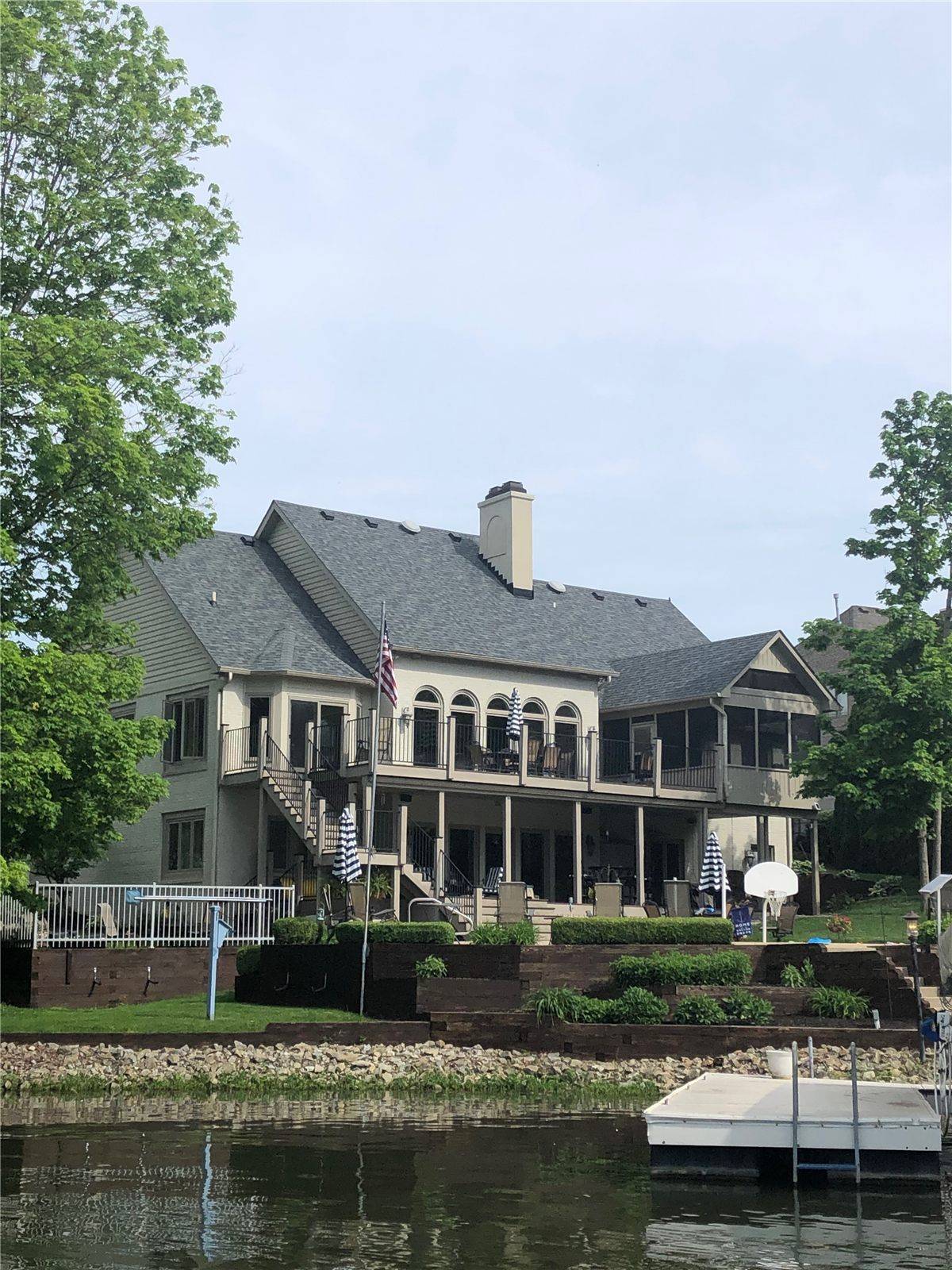 Lake house with new gray architectural shingles, photographed from the water