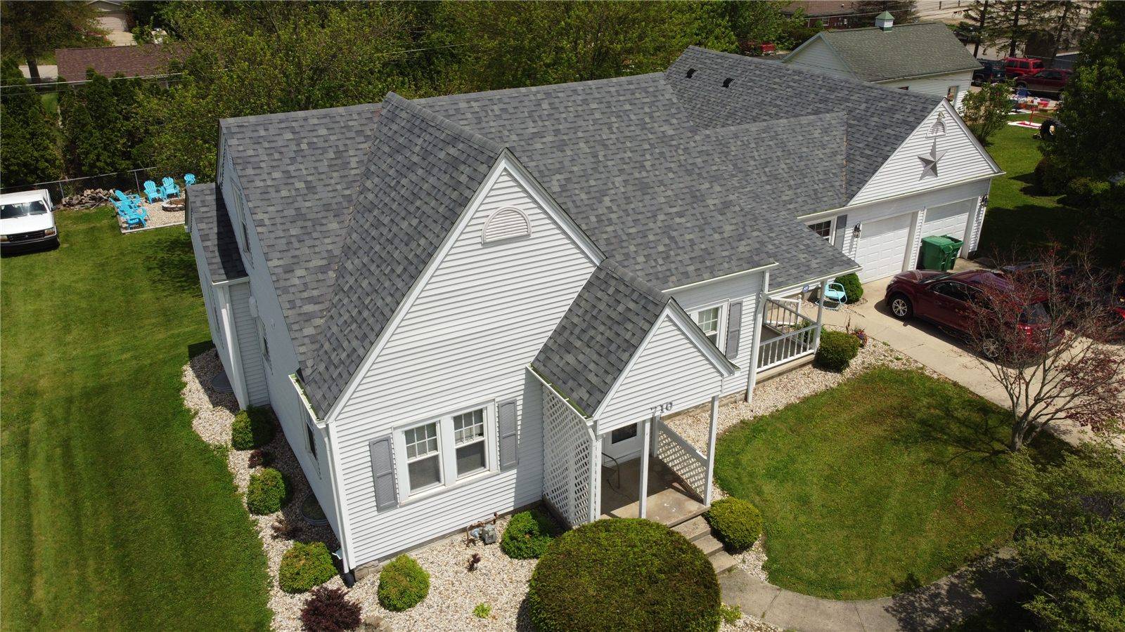 A new gray shingle roof by Tabor on a white house, seen from a drone
